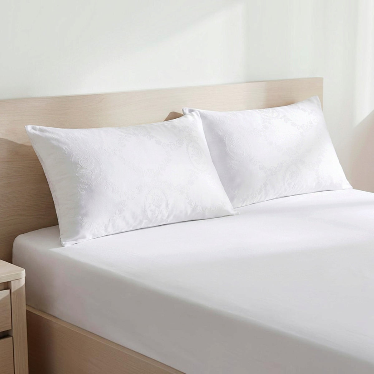 Due salvacuscini Daunex Medaglione bianchi da 50×80 cm posizionati su un letto matrimoniale